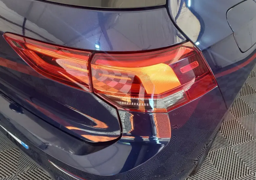 Gros plan sur le feu arrière droit d'une Volkswagen Golf bleue 2022, soulignant la teinte profonde et les lignes nettes.