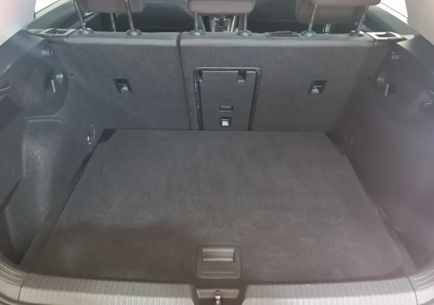 Vue intérieure du coffre noir de la Volkswagen Golf 1.5 ETSI 2022 avec banquette arrière rabattable et trappe centrale.