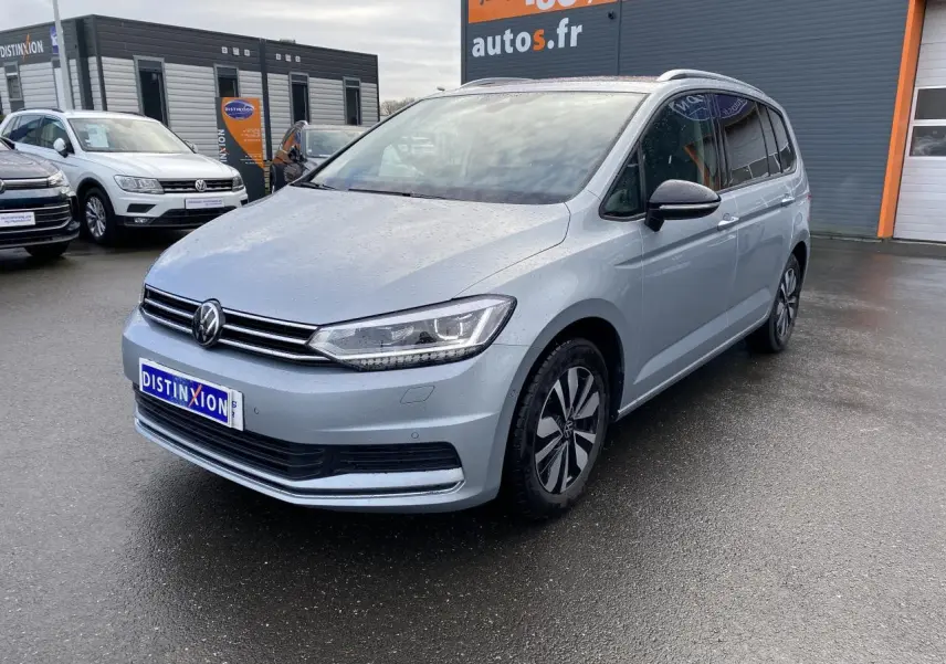 Volkswagen Touran 2025 Oyster argent métallisé en 3/4 avant droit, avec projecteurs IQ.Light et jantes distinctives.