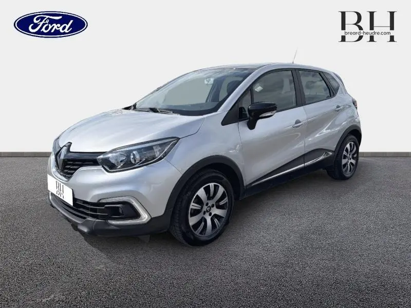 Vue 3/4 avant droit d'un Renault Captur gris platine avec jantes alliage et rétroviseurs noirs sur fond neutre.