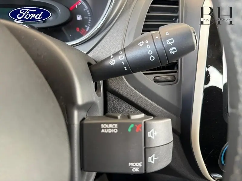 Gros plan sur la commande audio au volant et le commodo d’essuie-glace d’un Renault Captur gris platine, intérieur noir.