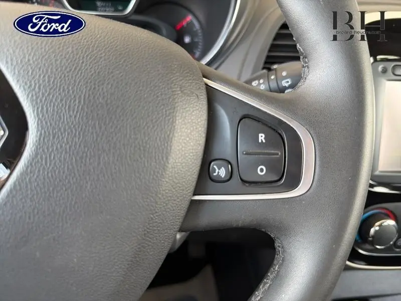 Gros plan sur les commandes au volant côté droit du Renault Captur gris platine, avec tableau de bord partiellement visible.