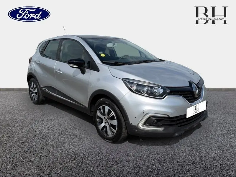 Renault Captur gris platine en 3/4 avant droit, avec jantes alliage et rétroviseurs noirs contrastés.