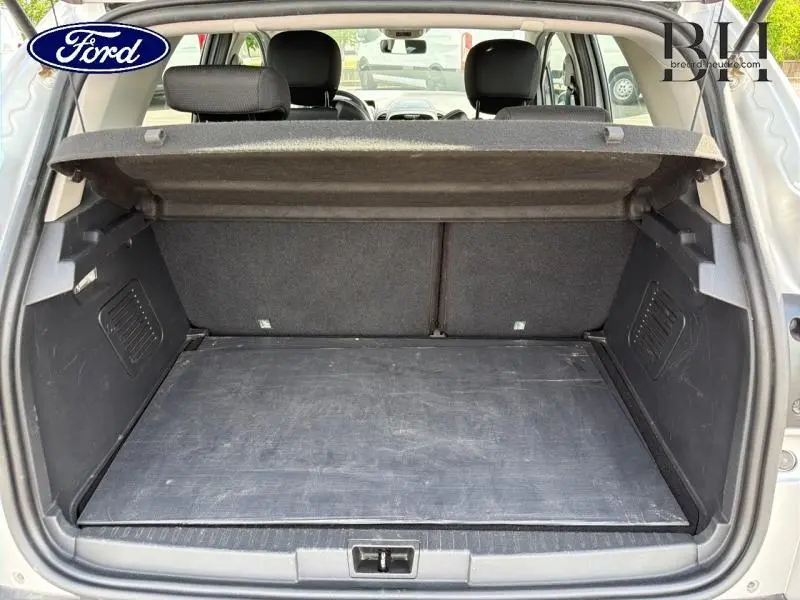 Coffre ouvert vu de l'arrière d'un Renault Captur gris platine, avec cache-bagages en place et banquette arrière visible.