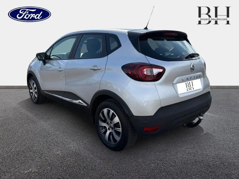 Vue 3/4 arrière droite d'un Renault Captur gris platine avec feux arrière LED et attelage visible.
