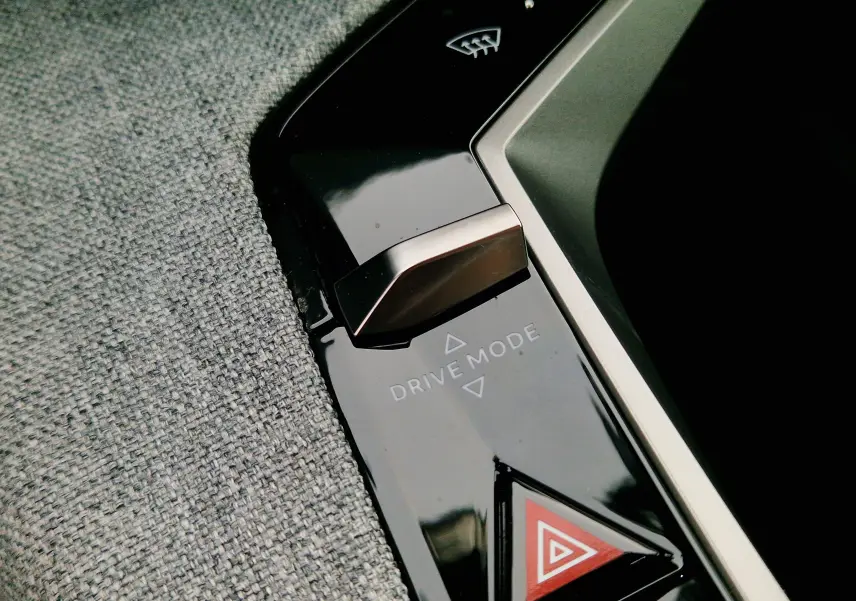 Gros plan sur le bouton Drive Mode et le bouton de warning triangulaire dans l’habitacle du Peugeot 3008 gris Artense.