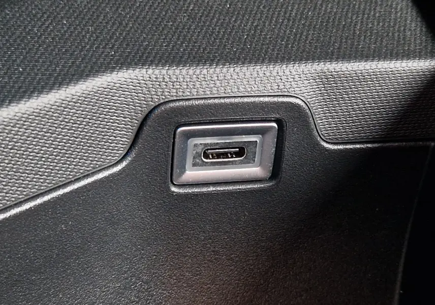 Gros plan sur un port USB-C intégré dans la console intérieure noire du Peugeot 3008 gris Artense 2025.