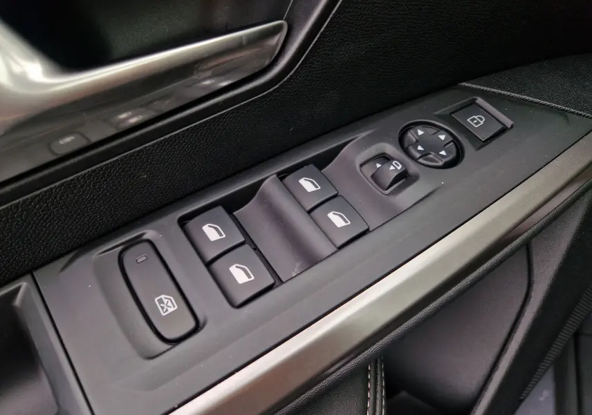 Gros plan sur les commandes de lève-vitres et rétroviseurs côté conducteur du Peugeot 3008 gris Artense, finition Allure Business.