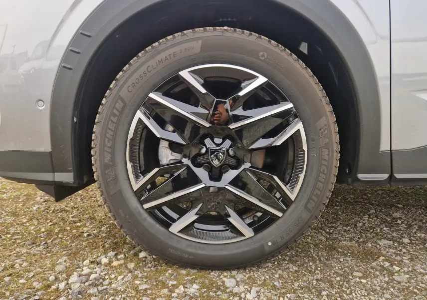 Gros plan sur la roue avant droite d’un Peugeot 3008 gris Artense, mettant en valeur la jante noire et argentée au design moderne.