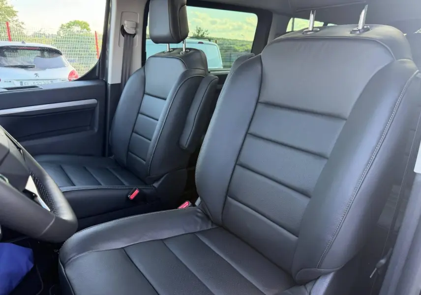 Vue intérieure rapprochée des sièges avant en cuir noir du Citroën Spacetourer XL gris titane, avec accoudoir central côté passager.