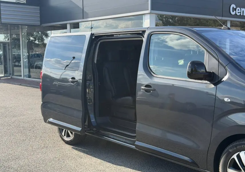 Vue latérale droite d’un Citroën Spacetourer XL gris titane avec porte coulissante ouverte dévoilant l’intérieur noir.