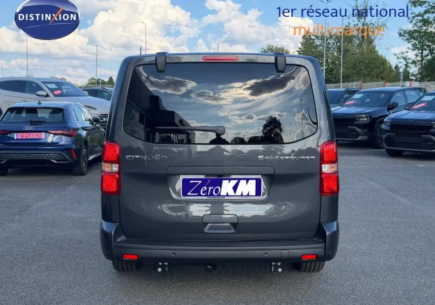 Vue arrière d'un Citroën Spacetourer XL gris titane avec vitres arrière surteintées et hayon fermé sur parking.