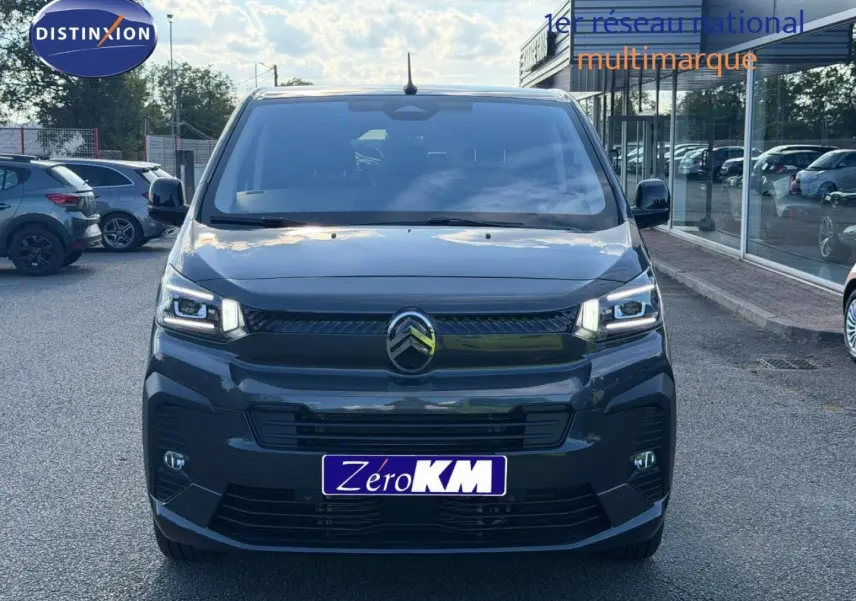 Vue avant d'un Citroën Spacetourer XL gris titane avec phares LED allumés sur parking extérieur.