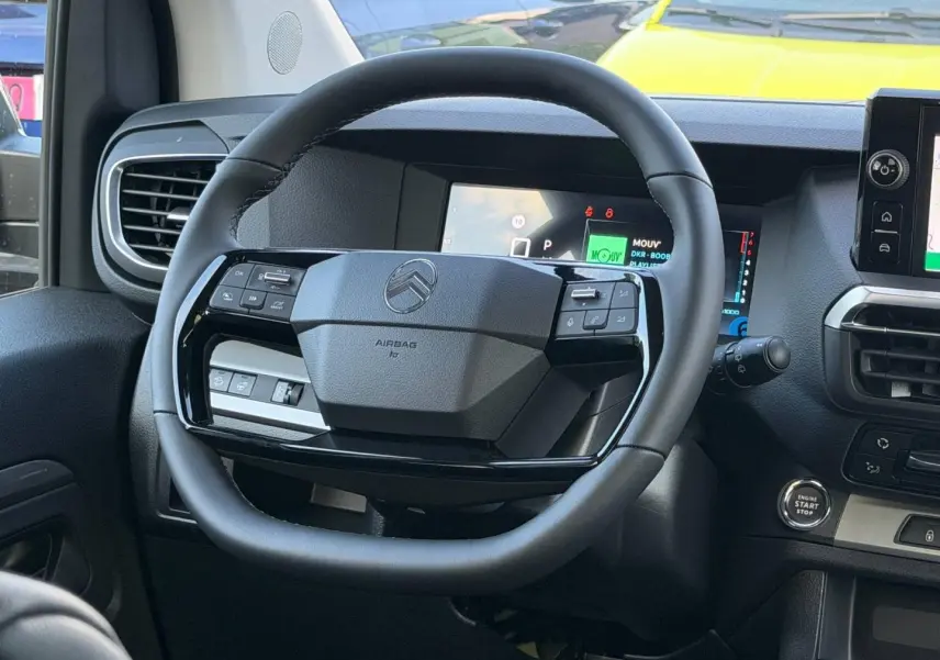Vue intérieure centrée sur le volant noir du Citroën Spacetourer XL 2026 avec tableau de bord numérique en arrière-plan.