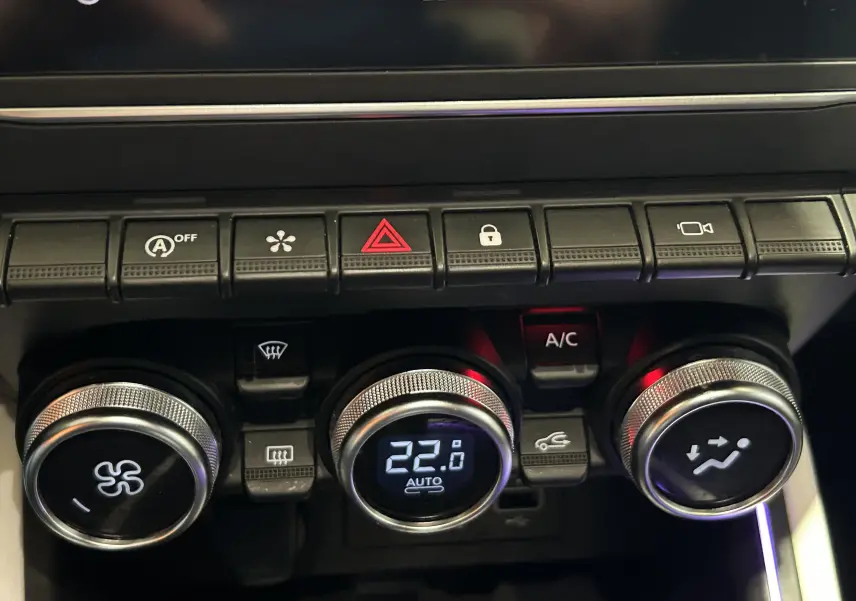 Gros plan sur la console centrale de la Renault Clio V TCe 90 TECHNO 2023, montrant les commandes de climatisation digitales.