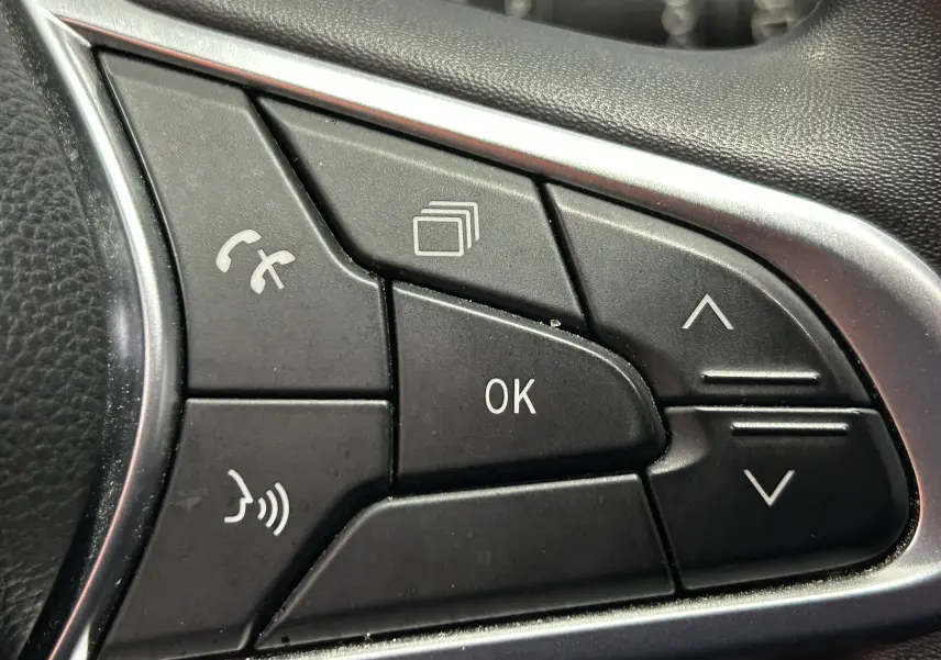 Gros plan sur les commandes au volant noir de la Renault Clio V TCe 90 TECHNO 2023, avec boutons multifonctions et cadre argenté.