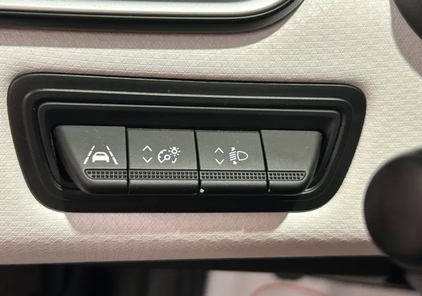 Boutons de réglage de l'aide à la conduite et des phares sur le tableau de bord gris clair d'une Renault Clio V TCe 90 TECHNO 2023.