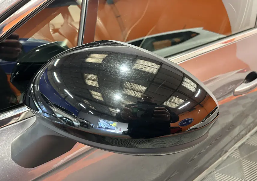 Rétroviseur noir brillant côté gauche d'une Renault Clio V TCe 90 TECHNO gris 2023 avec caméra 360° visible.