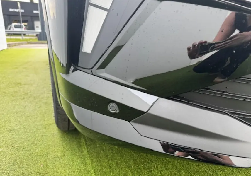 Gros plan sur le pare-chocs avant noir étoilé du Renault Espace VI avec capteur de stationnement intégré.