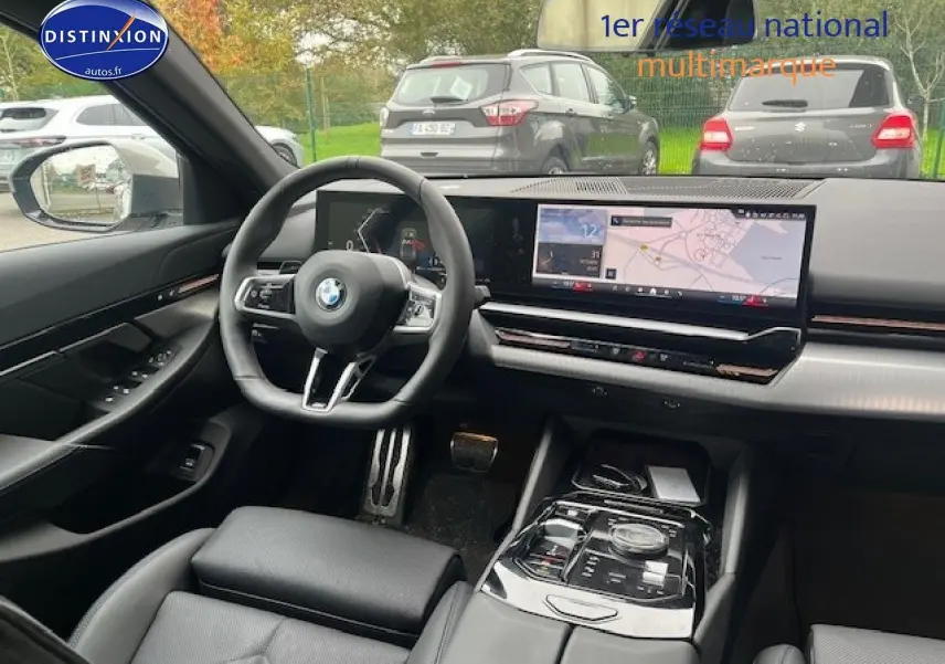 Vue intérieure avant de la BMW Série 5 gris, avec tableau de bord numérique et large écran tactile GPS.