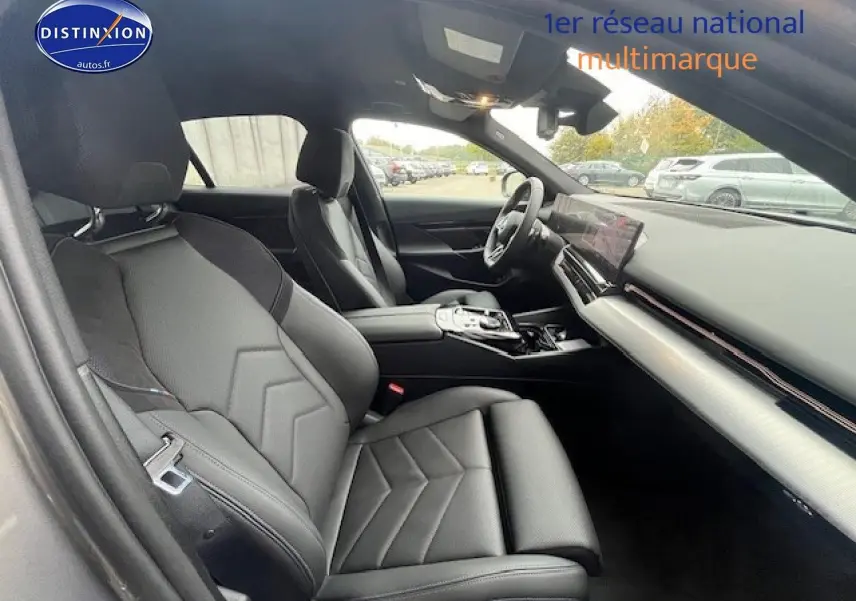 Vue intérieure côté conducteur de la BMW Série 5 520da 2024 avec sièges sport cuir noirs et tableau de bord moderne.