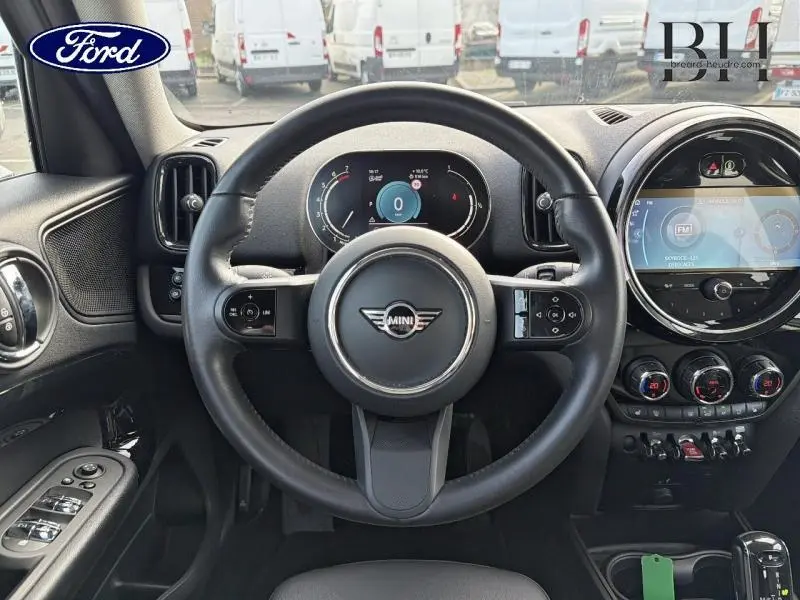 Vue intérieure centrée sur le volant cuir multifonction d'une MINI Countryman 2023 avec tableau de bord numérique et écran tactile rond.