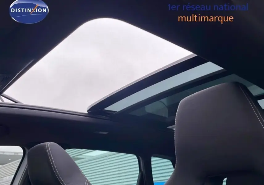 Toit panoramique ouvert vu de l'intérieur arrière d'un Skoda Karoq argent avec sièges noirs et surpiqûres blanches.