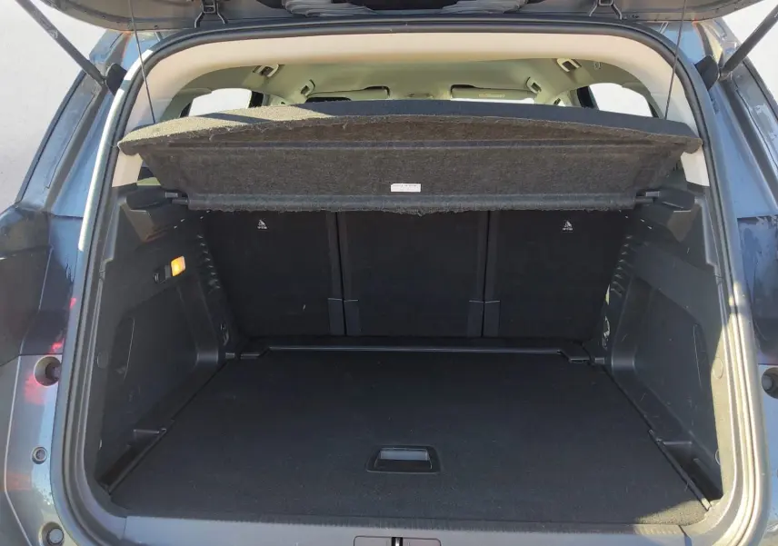 Coffre ouvert vu de l'arrière d'un Citroën C5 Aircross gris platinium, montrant l'espace de chargement vide et la tablette cache-bagages relevée.