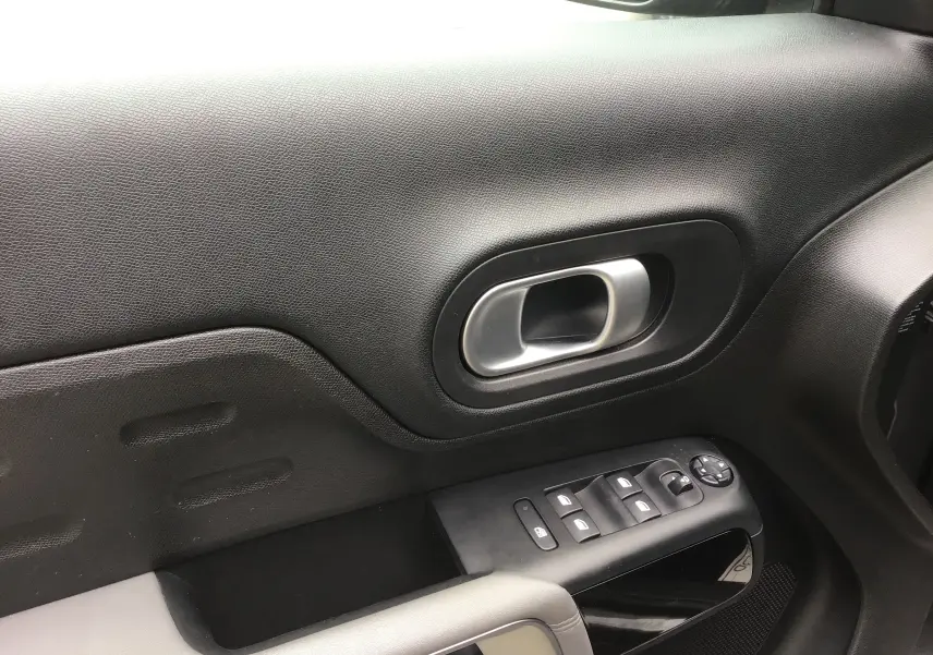 Gros plan sur la poignée intérieure et les commandes de fenêtre côté conducteur du Citroën C5 Aircross gris platinium.