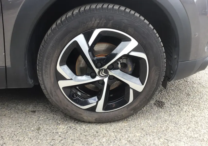 Gros plan sur la roue avant droite d’un Citroën C5 Aircross gris platinium avec jante alliage noire et argentée.