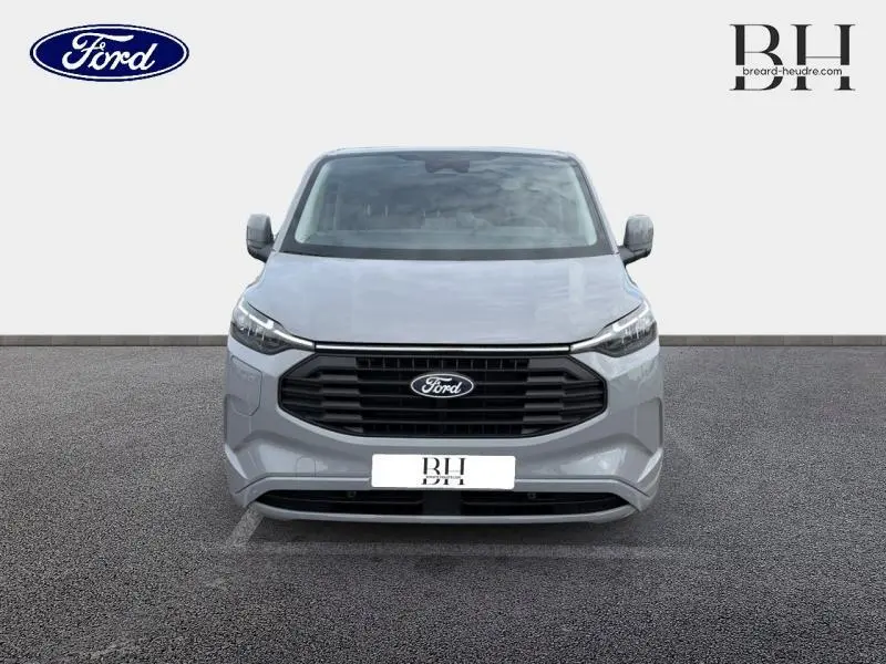 Vue frontale du Ford Transit Custom Fourgon gris Matter Spéciale avec calandre noire et logo Ford centré.