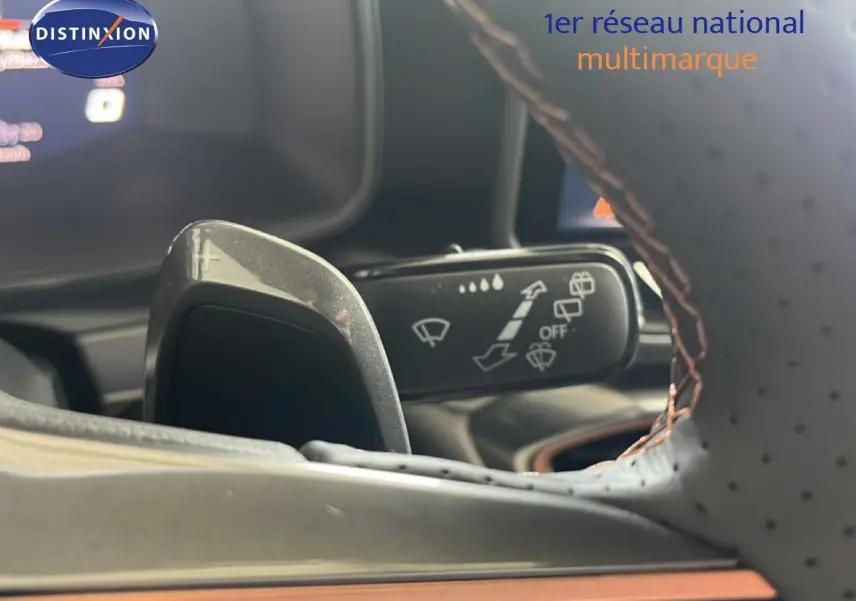 Gros plan sur la palette de changement de vitesse et le commodo d’essuie-glace, volant cuir perforé avec surpiqûres orange.