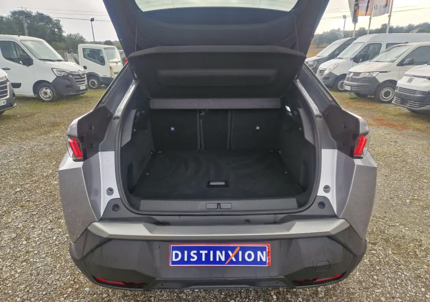 Vue arrière du Peugeot 3008 gris Artense avec coffre ouvert, montrant l'espace de chargement vide et les feux arrière allumés.