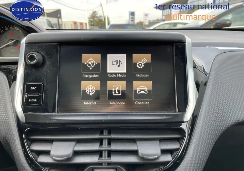 Écran tactile central du tableau de bord du Peugeot 2008 blanc de 2016, affichant les options de navigation et média.
