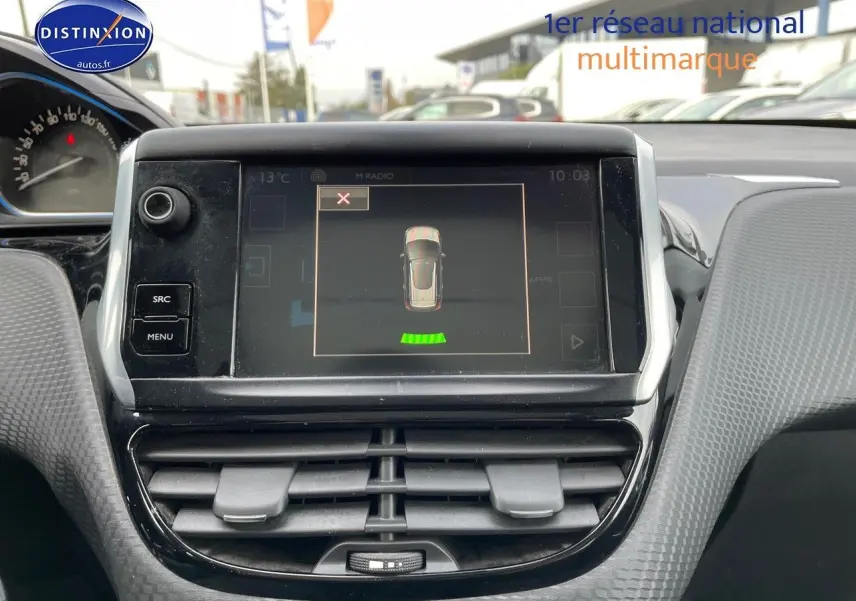 Vue rapprochée du tableau de bord de la Peugeot 2008 blanc, affichant l'écran central avec capteurs de recul actifs.