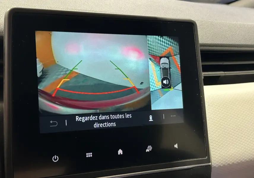 Écran intérieur de la Renault Clio V rouge montrant la caméra 360° en vue arrière et vue aérienne du véhicule.