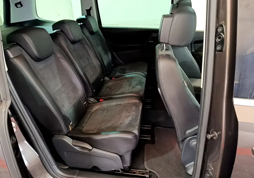 Vue latérale intérieure montrant la deuxième rangée de sièges en cuir noir du Volkswagen Sharan marron de 2017.