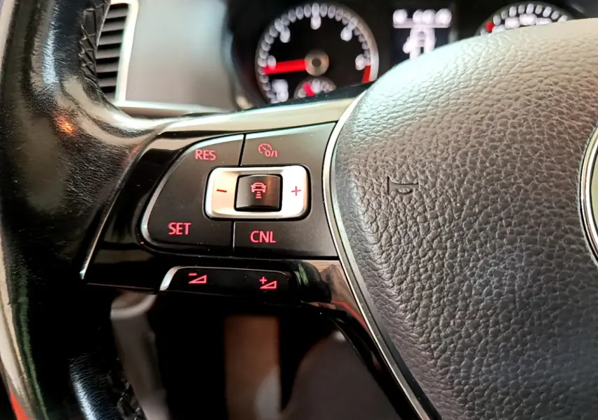 Gros plan sur le volant cuir noir de la Volkswagen Sharan 2017, avec commandes de régulateur adaptatif éclairées en rouge.