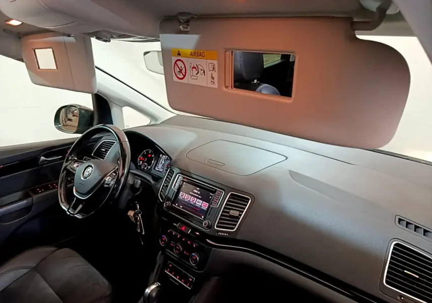 Intérieur avant du Volkswagen Sharan marron 2017, tableau de bord avec écran tactile et volant cuir multifonctions.
