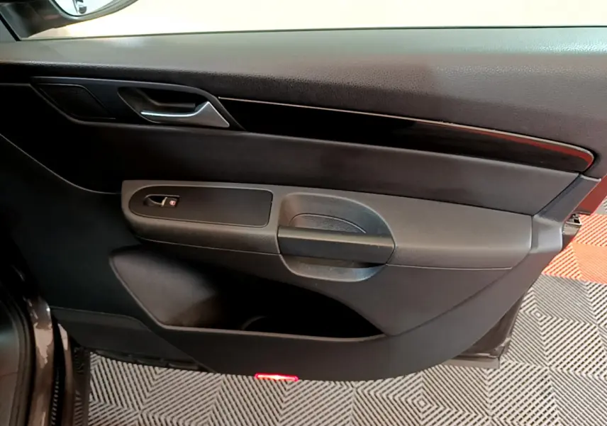 Vue rapprochée de la porte côté gauche noire du Volkswagen Sharan 2017 avec poignée et insert bois foncé.