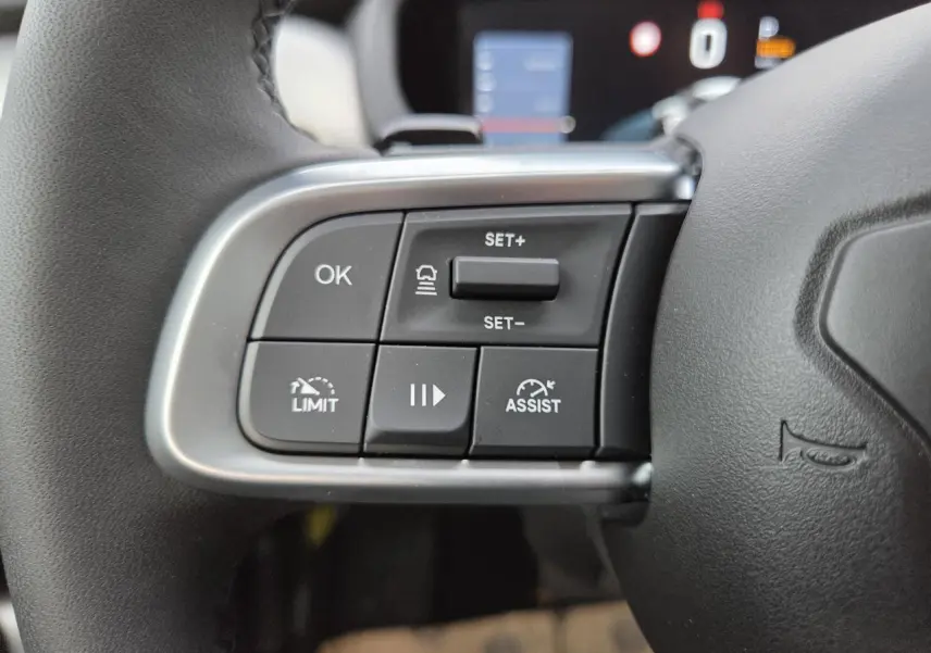 Gros plan sur les commandes au volant noir du Jeep Avenger 2025, avec boutons de régulateur et assistance de conduite.