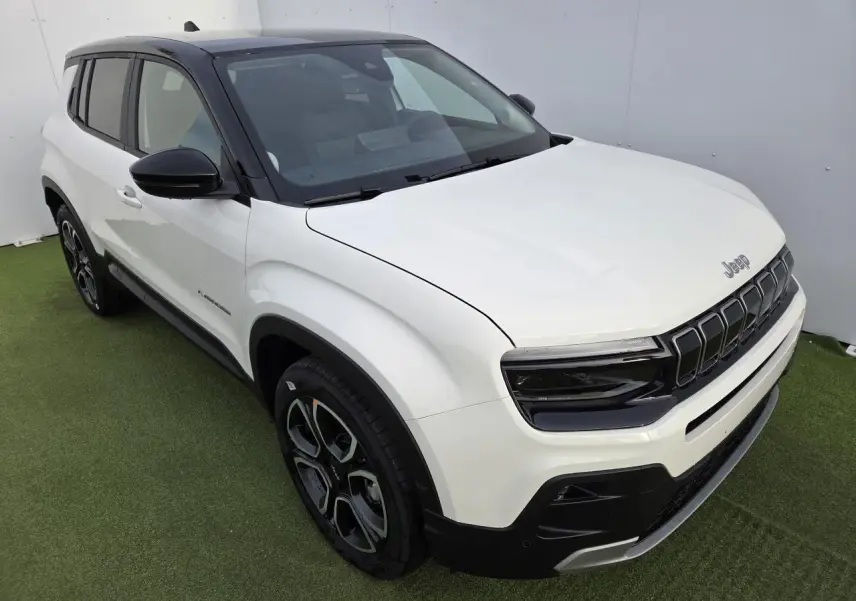 Jeep Avenger blanc Snow avec toit noir Volcano, vue 3/4 avant droit mettant en valeur la calandre gloss black.