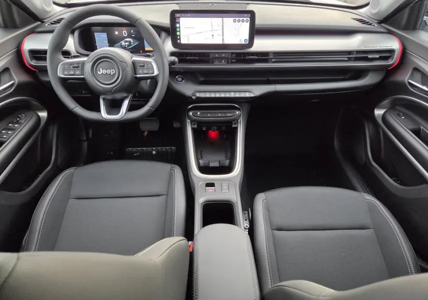 Vue intérieure frontale du Jeep Avenger 2025 avec tableau de bord noir, écran tactile central et volant multifonction.