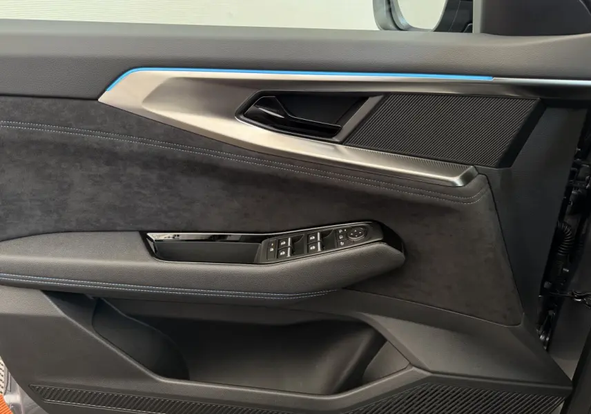 Gros plan sur la porte côté gauche du Renault Espace gris foncé, avec garniture noire et surpiqûres bleues élégantes.