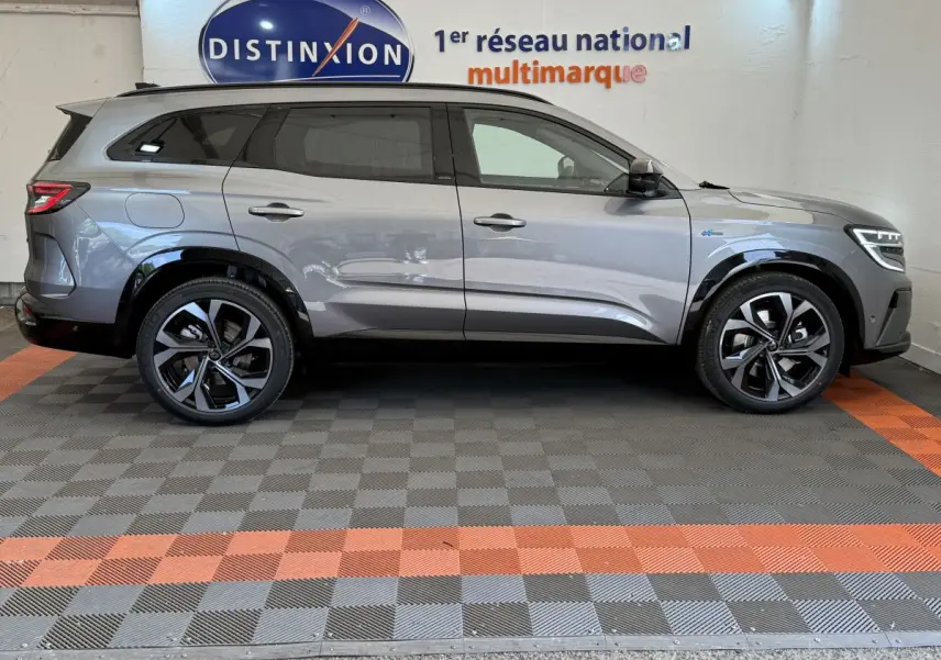 Profil côté gauche du Renault Espace esprit Alpine gris foncé 2025 avec jantes noires et toit noir en intérieur showroom.