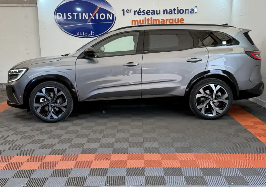Profil côté gauche d'un Renault Espace gris foncé esprit Alpine 7 places, roues alliage et toit noir visible en intérieur showroom.