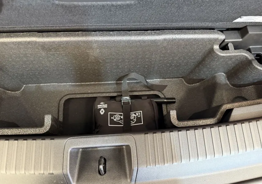 Compartiment de rangement sous le plancher du coffre du Renault Espace gris foncé, avec kit de réparation pneus visible.