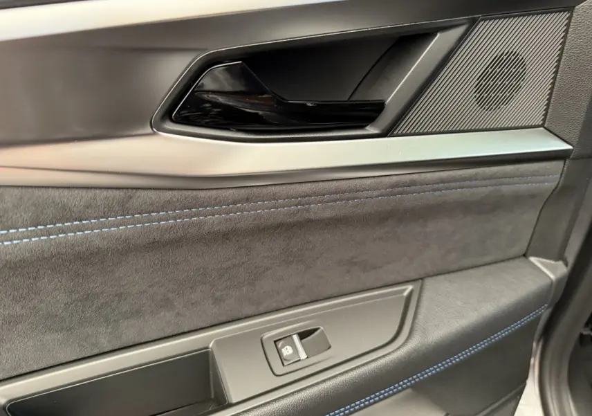 Gros plan sur la garniture intérieure de porte avant droite du Renault Espace gris foncé esprit Alpine 2025, avec surpiqûres bleues.