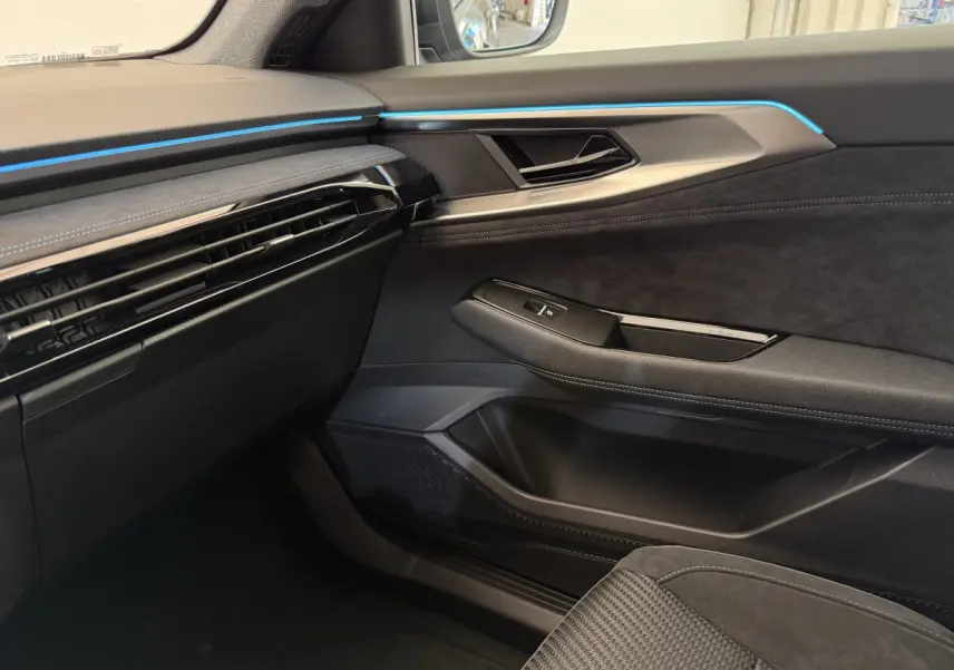 Intérieur côté passager du Renault Espace gris foncé 2025, avec éclairage d'ambiance bleu et matériaux noirs élégants.