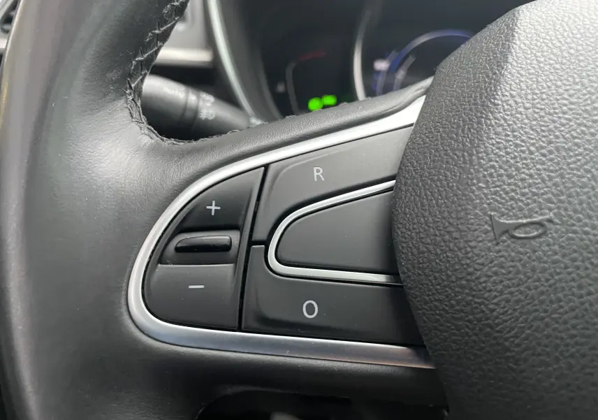 Gros plan sur les commandes de régulateur de vitesse au volant en cuir noir du Renault Kadjar gris titanium 2018.